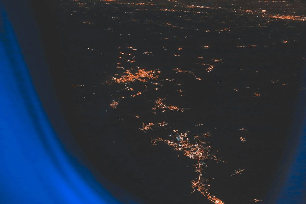 City lights far below an airplane window at night